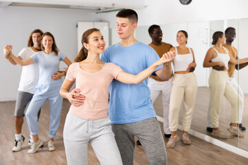 Class of positive multinational couples enjoing partner pair dancing during class together in...