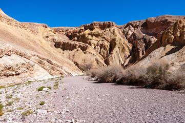 A desert landscape with a dry river bed and a rocky hillside