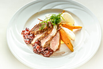 A plate of food with a piece of meat and a carrot on it