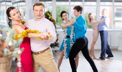 Couples dancing during Christmas - men and women dancing tango or samba next to the Christmas tree
