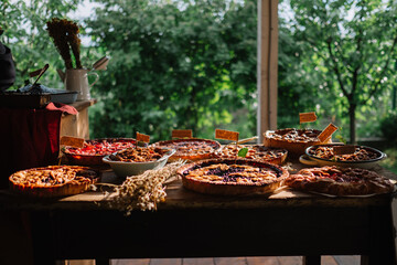 Variety of baked pies on a table with an outdoor backdrop