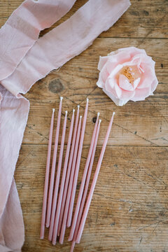 Pink candles and flower on rustic wooden table
