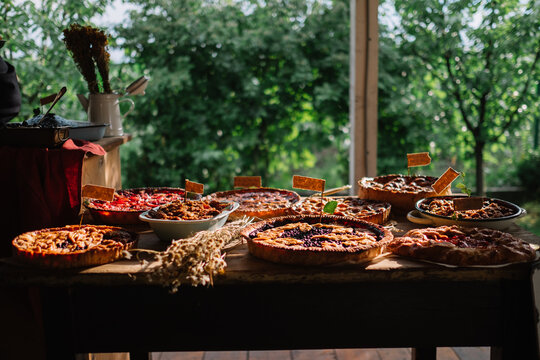 Variety of baked pies on a table with an outdoor backdrop