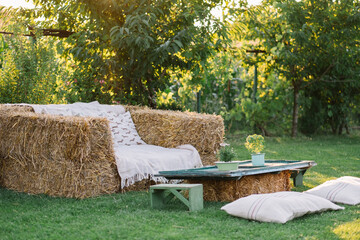 Hay bale couch and table set up in a serene garden.