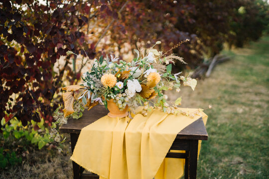 Floral display in earthy tones on wooden table.