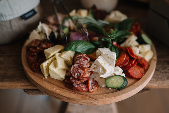 Cheese and cured meats on a wooden charcuterie board.