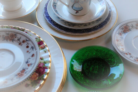 close-up of random mismatched porcelein china plates saucers dishes decluttering table organization background 