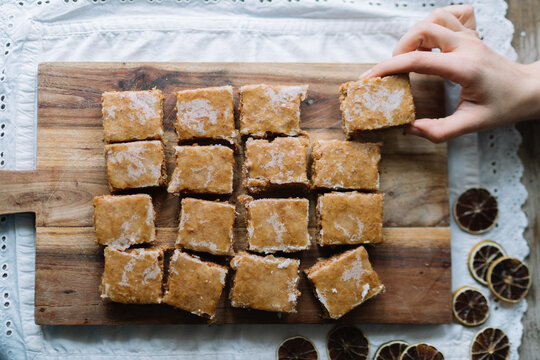 Hand picking moist brown square with white glaze.