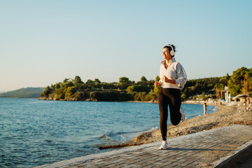 Young caucasian woman running or jogging on the beach at sunset	