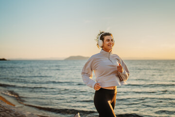 Young caucasian woman running or jogging on the beach at sunset	