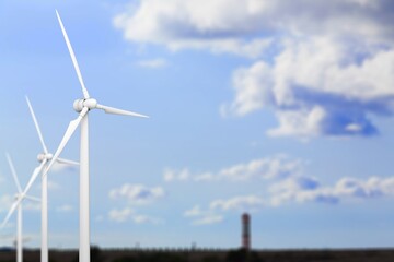 Fototapeta premium A row of tall white wind turbines at blue sky