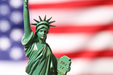 Fototapeta premium Statue of Liberty against flag of USA, closeup. Space for text