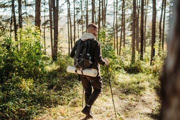 Young caucasian man hiking or trekking through the forest	