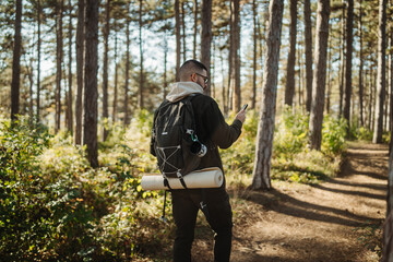 Young caucasian man hiking or trekking through the forest	