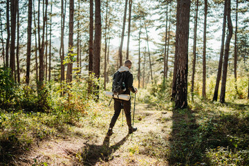 Obraz premium Young caucasian man hiking or trekking through the forest 