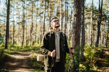 Obraz premium Young caucasian man hiking or trekking through the forest 