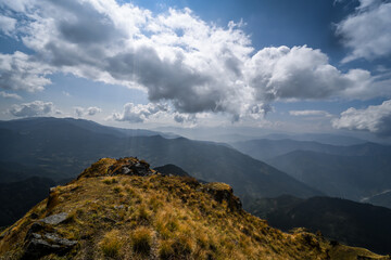 A beautiful mountain cliff overlooking Annapurna range of Nepal under clear blue sky and clouds