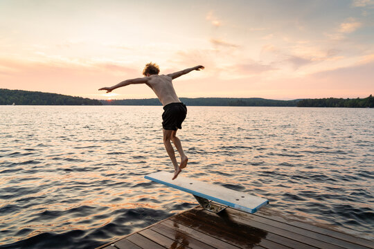 Teen Diving into Lake from Canadian Cottage Dock at Sunset
