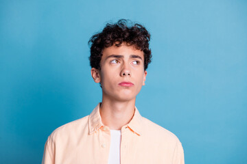 Obraz premium Young man with curly hair posing against blue background wearing a casual shirt