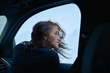Lady relishing winter air in snowy car