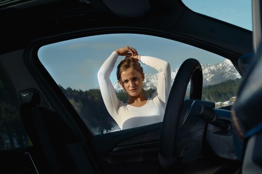 Woman stretching in a car with mountain backdrop