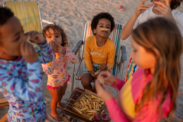 A group of kids eating fish and chips at the beach