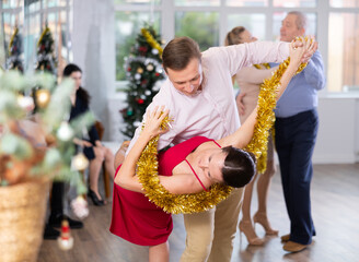 Christmas and New Year holiday - couples dancing with tinsel near the Christmas tree