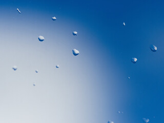 窓についた雨粒と晴れた青空
