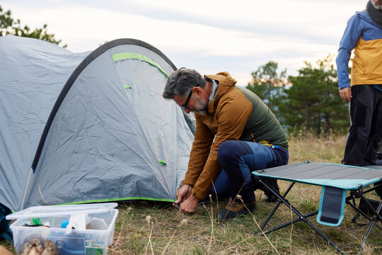 Man sets up a tent in a camp