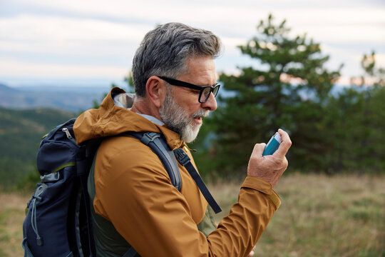 Portrait of a man holding an inhaler on a mountain