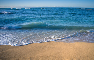 Turquoise Blue Ocean Wave Breaking on a Sandy Beach in Waikiki, Hawaii.