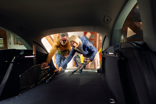 People pack their camping stuff in the back of a car