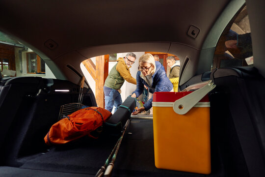 People pack their camping stuff in the back of a car