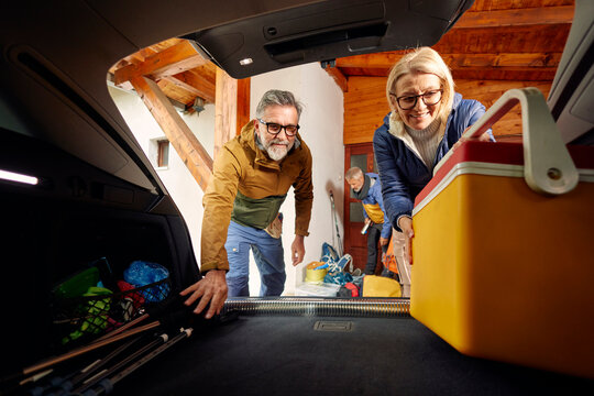 Couple pack their camping stuff in the trunk of a car