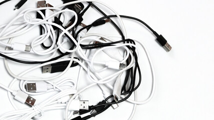 top down view close up of many tangled usb cords cables on white cluttered technology communication...