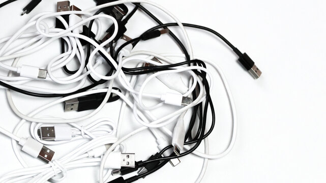 top down view close up of many tangled usb cords cables on white cluttered technology communication background