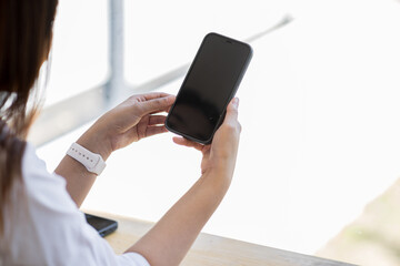 Mockup woman hand holding using smart phone with white blank screen at coffee shop, mobile app design and advertising,SME entrepreneur online marketing