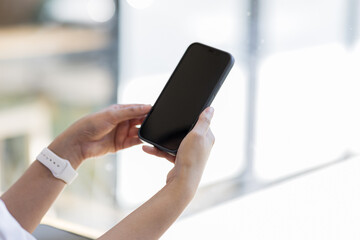 Mockup woman hand holding using smart phone with white blank screen at coffee shop, mobile app design and advertising,SME entrepreneur online marketing