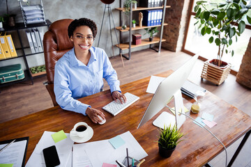Confident businesswoman in elegant blue blouse working in modern office with positive energy and...