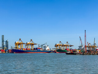 Naklejka premium The biggest port in Bangkok with loaded freight ship and cargo handling equipment on the side of Chao Phraya river.