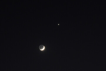 new moon and Venus shining above a house and tree during sun set 