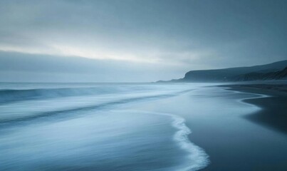 Fototapeta premium A serene beach scene at dusk with gentle waves and a misty atmosphere.