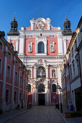 Fototapeta premium Narrow, cobbled street and historic facade of a Baroque religious church in the city of Poznan