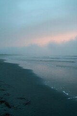 Fototapeta premium A serene beach scene at dusk, shrouded in mist and soft colors.