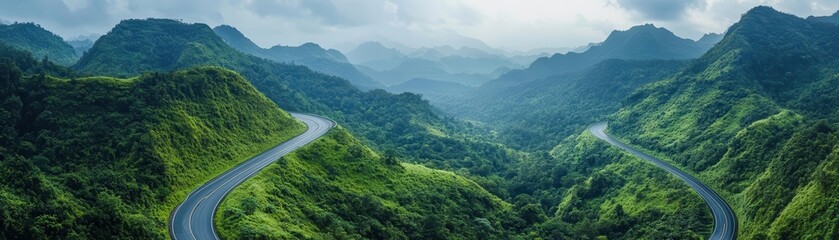 Fototapeta premium Aerial view of a curving highway surrounded by lush green mountains, symbolizing freedom and exploration, Mountain range sweeping road