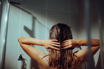 Woman in the shower Rinsing her Hair with Water. Girl taking care of her beautiful hair massaging her scalp
