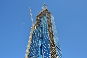 Obraz premium A tall skyscraper under construction against a clear blue sky.