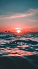 Fototapeta premium A serene sunset over calm ocean waters, reflecting warm colors.