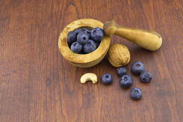 Wooden pestle and mortar with nuts and blueberries