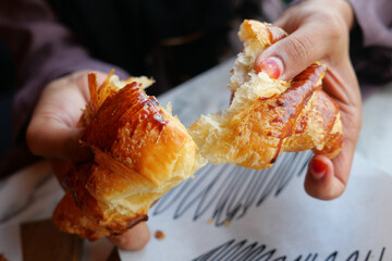 A detailed closeup view of hands breaking apart a fresh, warm croissant © Towfiqu Barbhuiya 